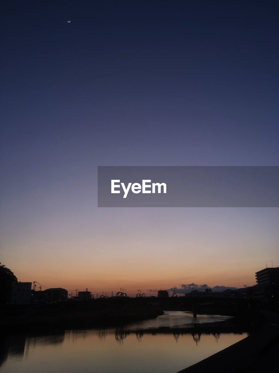 SCENIC VIEW OF RIVER AGAINST CLEAR SKY AT SUNSET