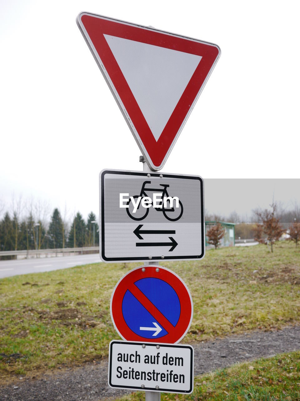 Close-up of road sign on field against clear sky