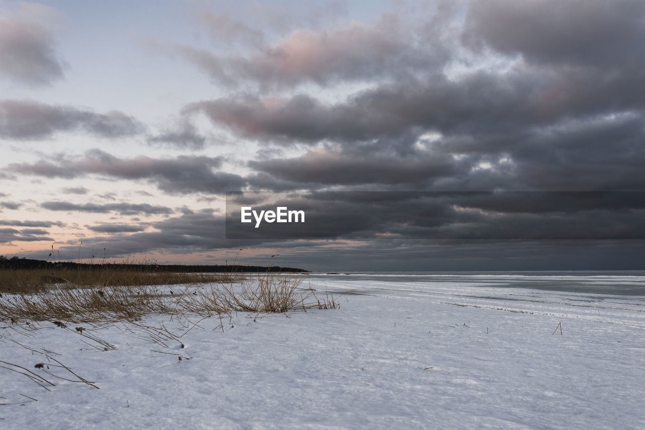 SCENIC VIEW OF SEA AGAINST SNOW COVERED LAND