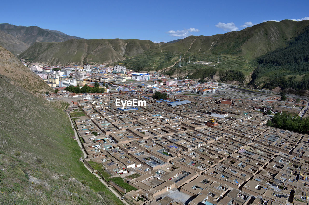 HIGH ANGLE VIEW OF TOWNSCAPE BY MOUNTAINS AGAINST SKY