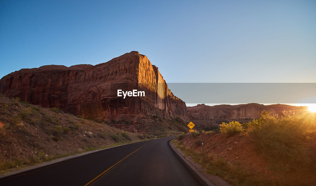 ROAD AMIDST ROCK FORMATION AGAINST CLEAR SKY