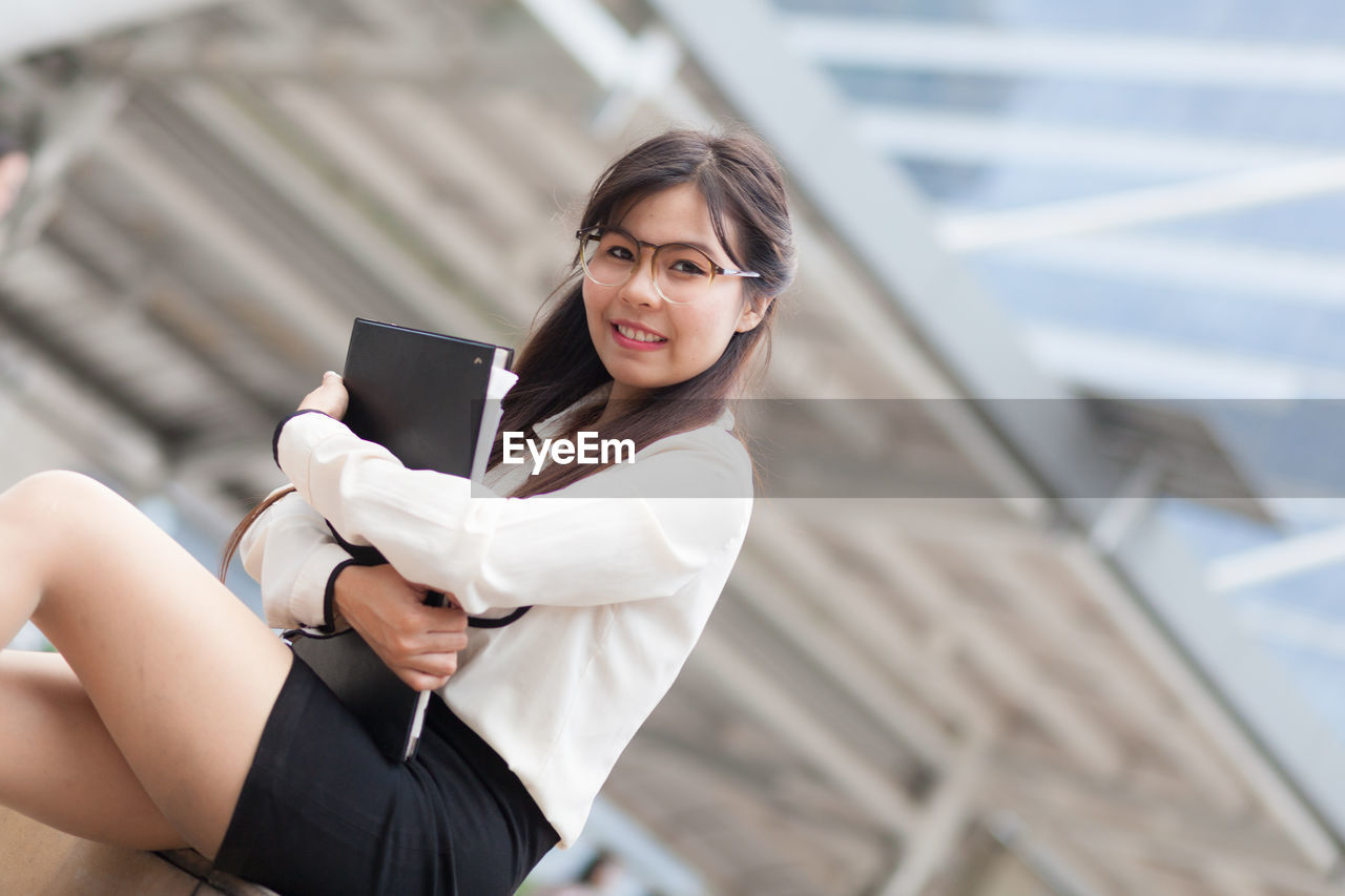 Portrait of young businesswoman with file on steps