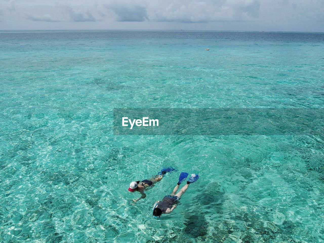 High angle view of people snorkeling in turquoise sea against sky