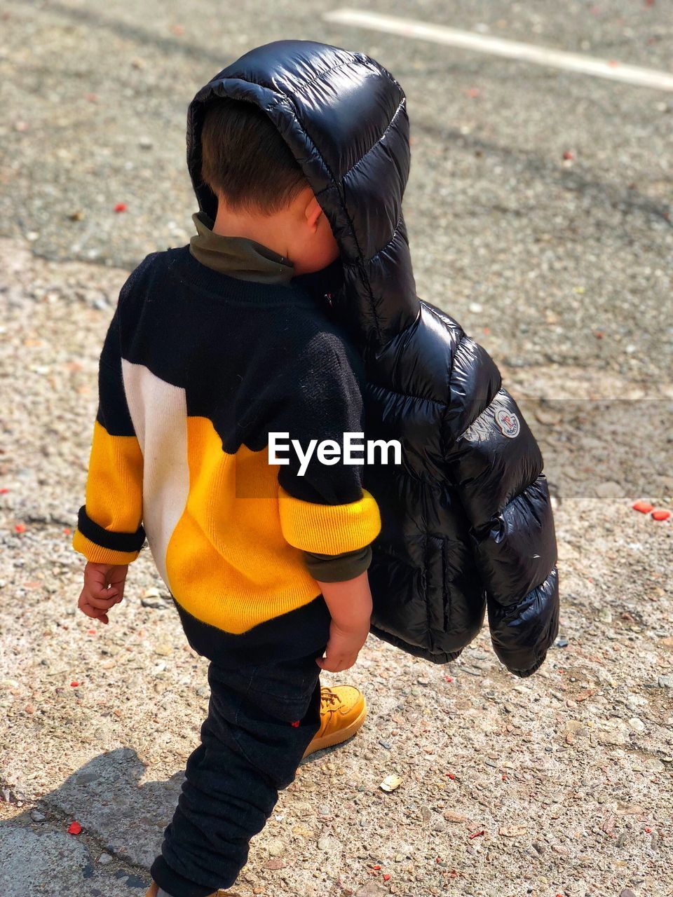 High angle view of boy wearing jacket while walking on street