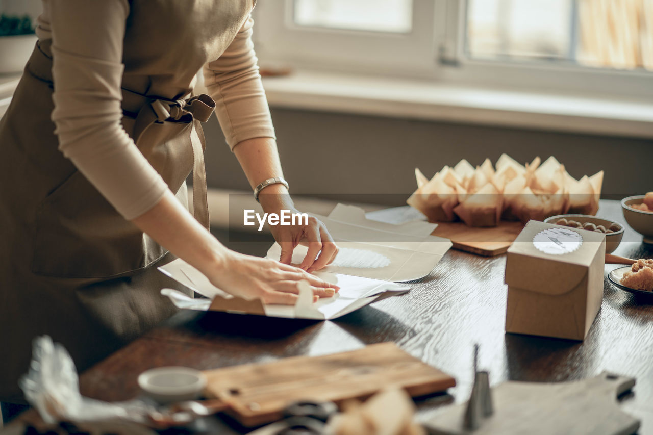 Women hands pack cupcakes in box. food delivery. birthday. bakery chef baking pastry in kitchen