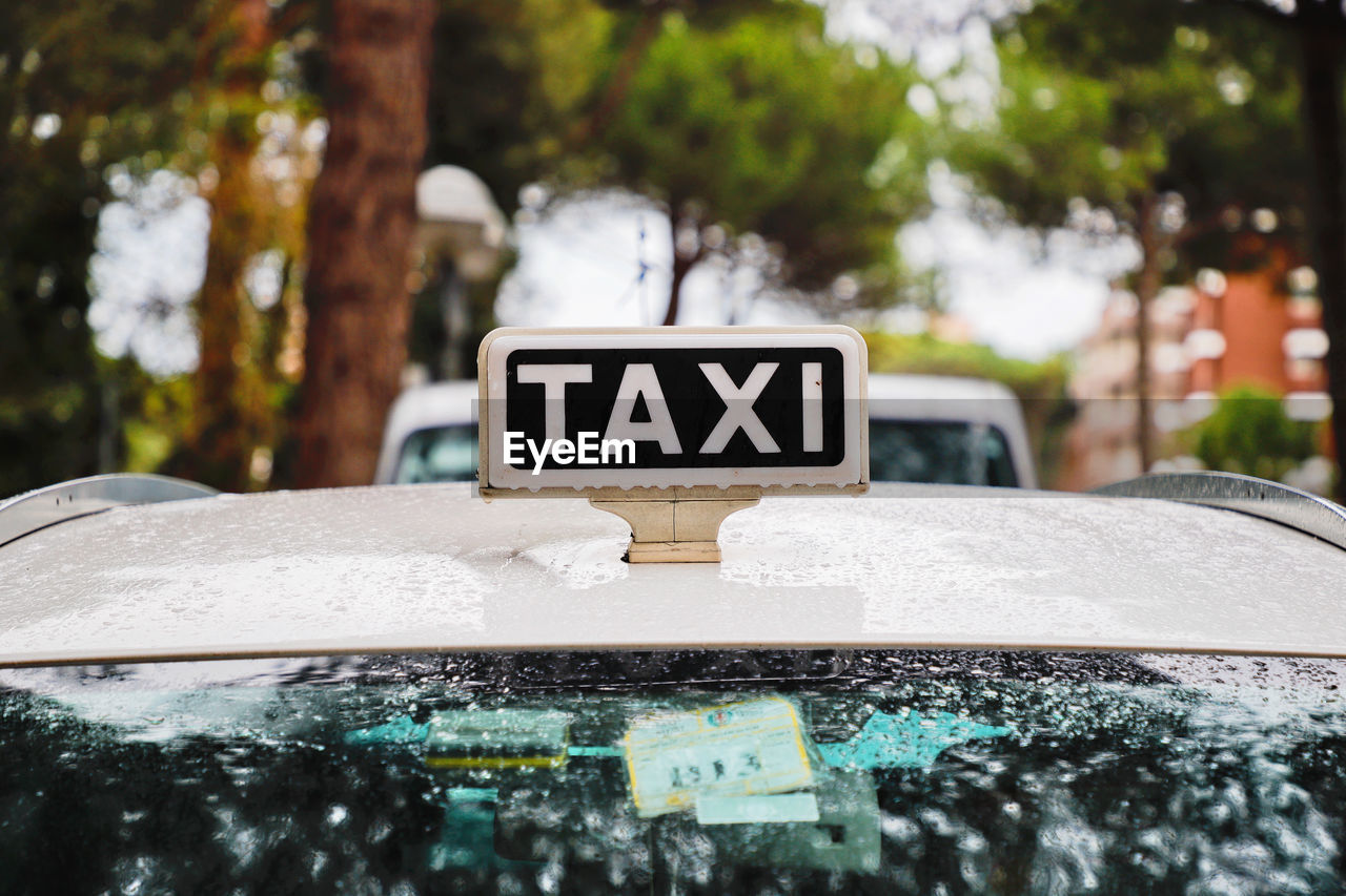 Raindrops Rainy Days Road Sign Taxi Text Transportation Capital Letter Car Close-up Communication Day Focus On Foreground Information Information Sign Land Vehicle Mode Of Transportation Motor Vehicle Nature No People Number Outdoors Selective Focus Text Transportation Tree Water Western Script Window Windshield
