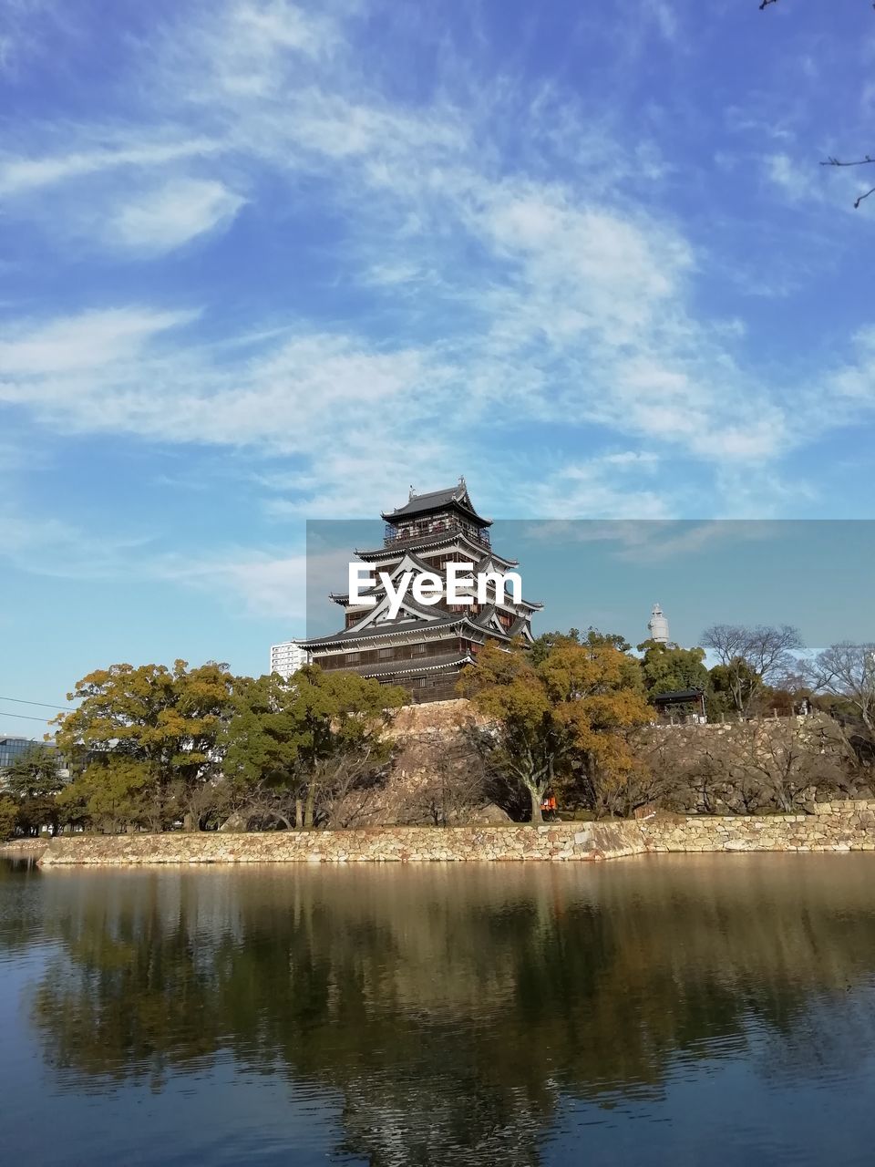 View of castle by lake against cloudy sky