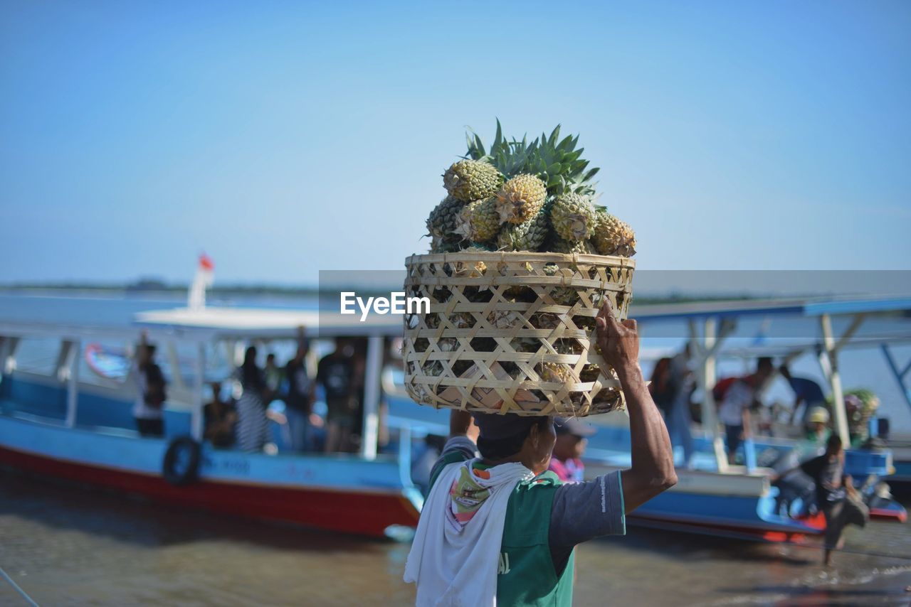 Man carrying pineapples in wicker basket at beach