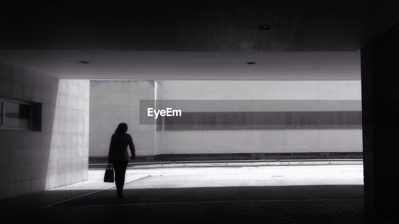 REAR VIEW OF WOMAN WALKING IN CORRIDOR OF BUILDING