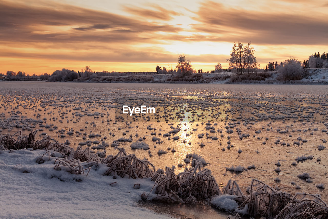 The sun rises over the frozen river at the rural finland. 