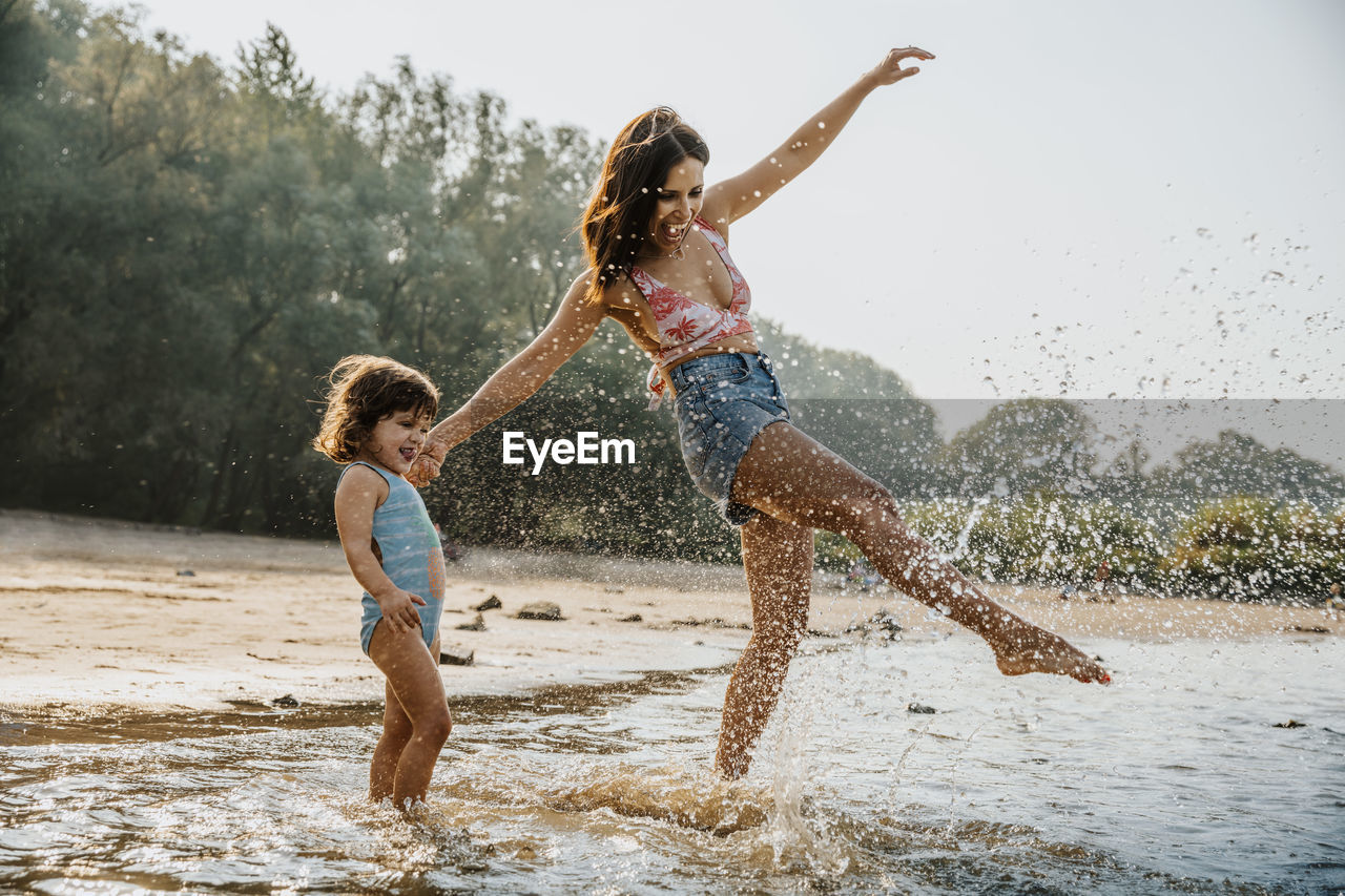 Mother and daughter enjoying in water at beach