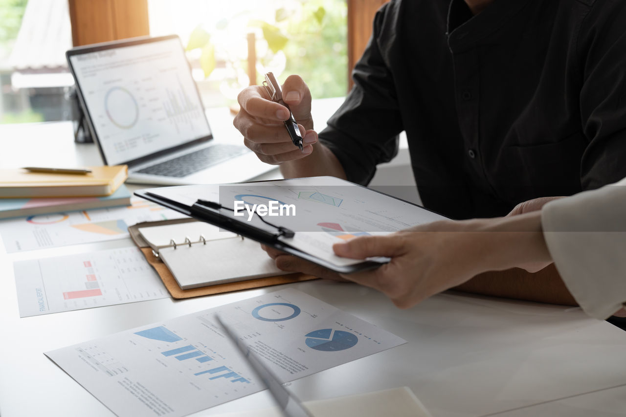 midsection of business people working on table