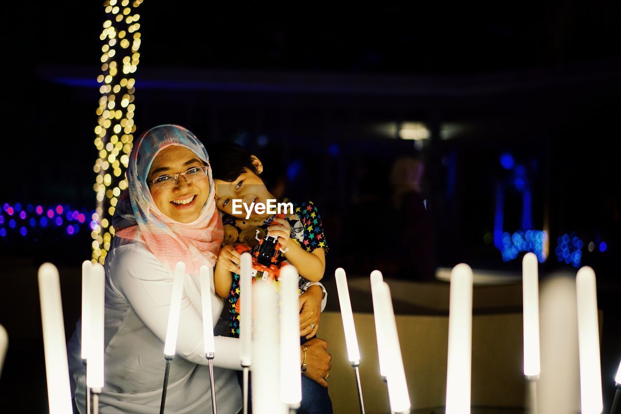 Portrait of mother and son with illuminated lighting equipment at night