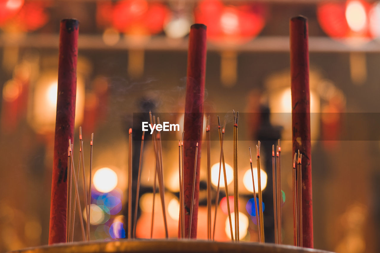 Close-up of burning incense sticks in temple at night