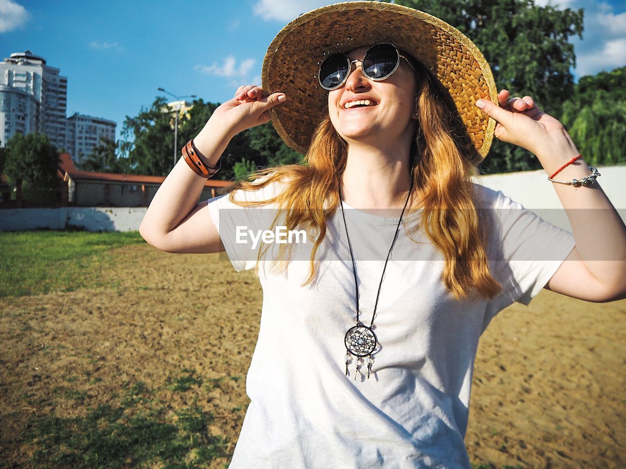 Smiling young woman wearing sunglasses and sun hat 