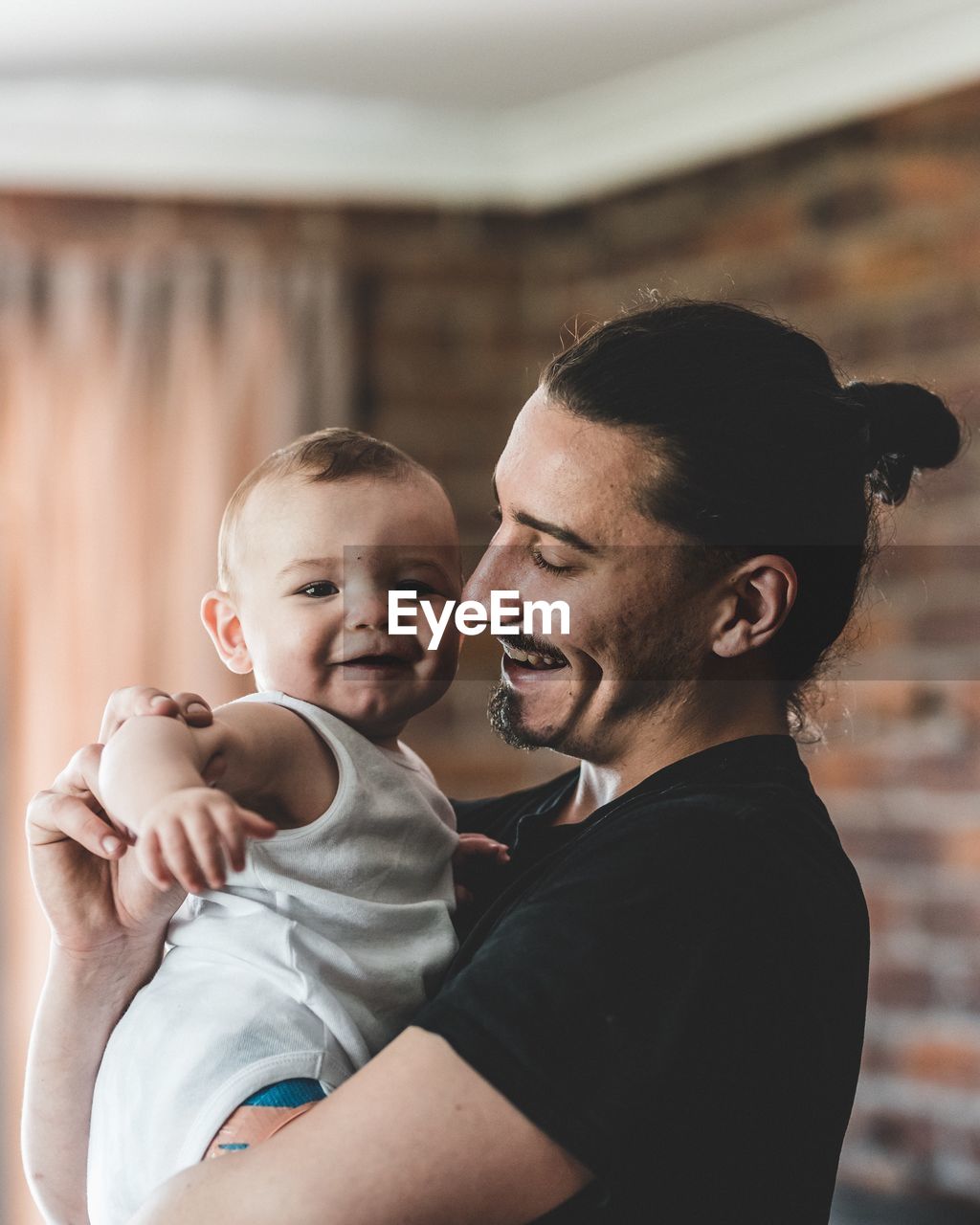 Side view of smiling father carrying son at home