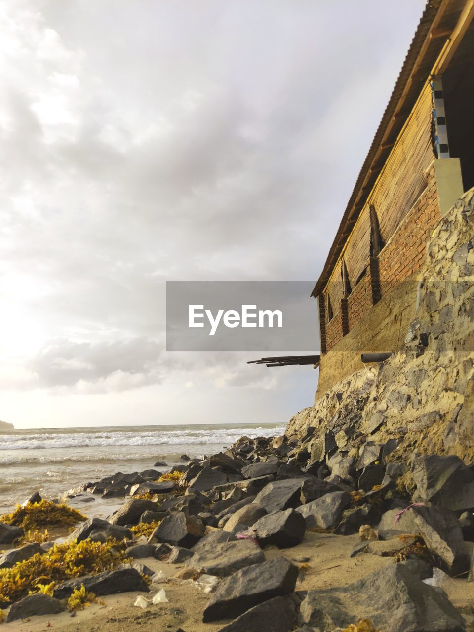 Rocks on beach by sea against sky