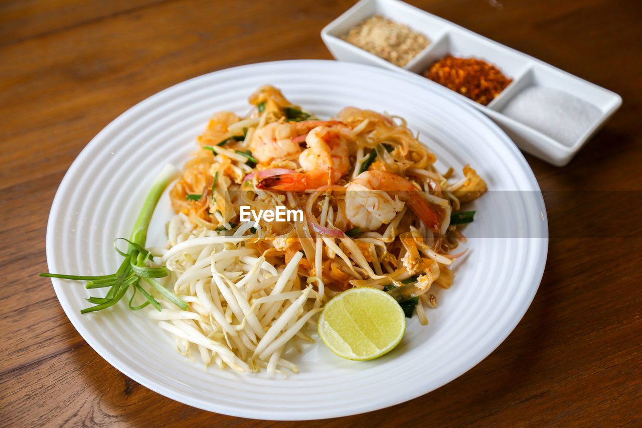 food and drink, food, healthy eating, plate, wellbeing, freshness, thai food, dish, pad thai, spaghetti, pasta, cuisine, italian food, table, meal, vegetable, no people, indoors, seafood, wood, produce, citrus fruit, lemon, meat, high angle view, herb, fruit, close-up, business, crustacean, restaurant, dinner, shrimp, asian food, spice, serving size, prawn, noodle