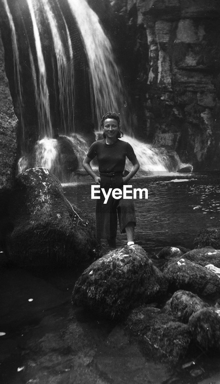 Portrait of woman standing against waterfall