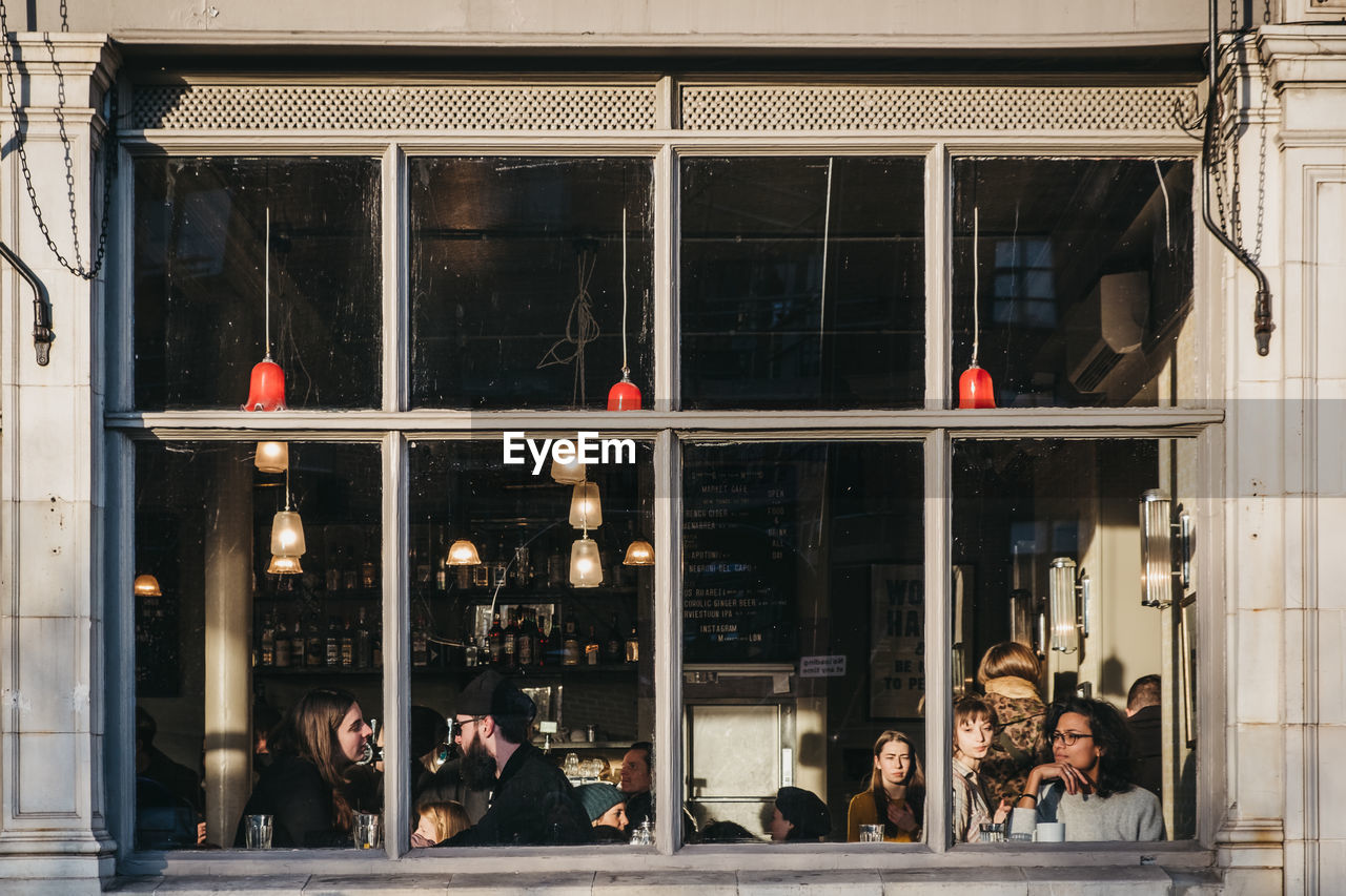 REFLECTION OF PEOPLE ON GLASS WINDOW IN BUILDING