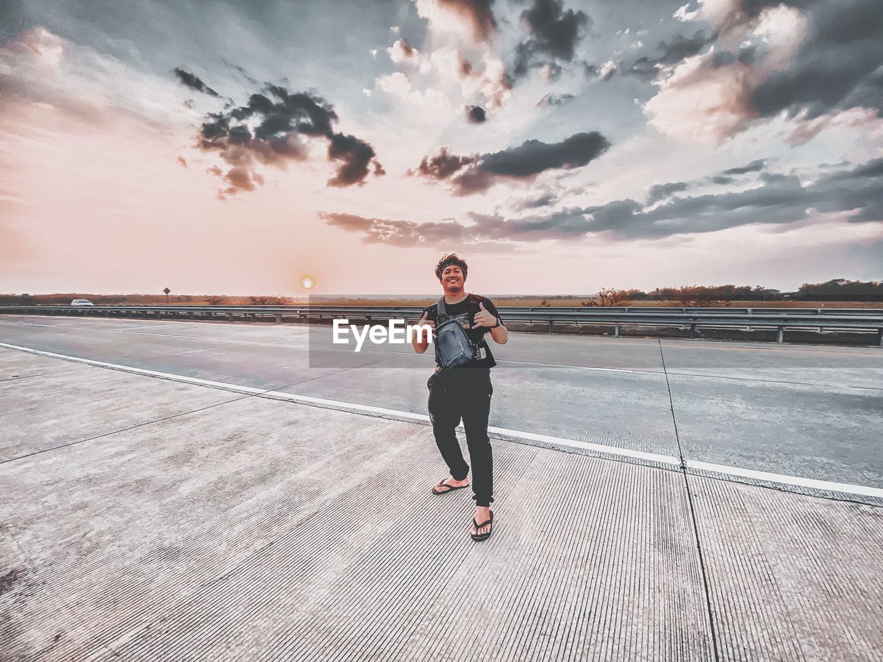 Full length of man standing on road against sky during sunset