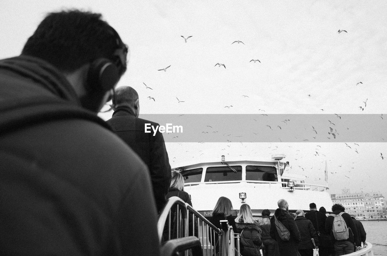 Rear view of people at harbor against sky