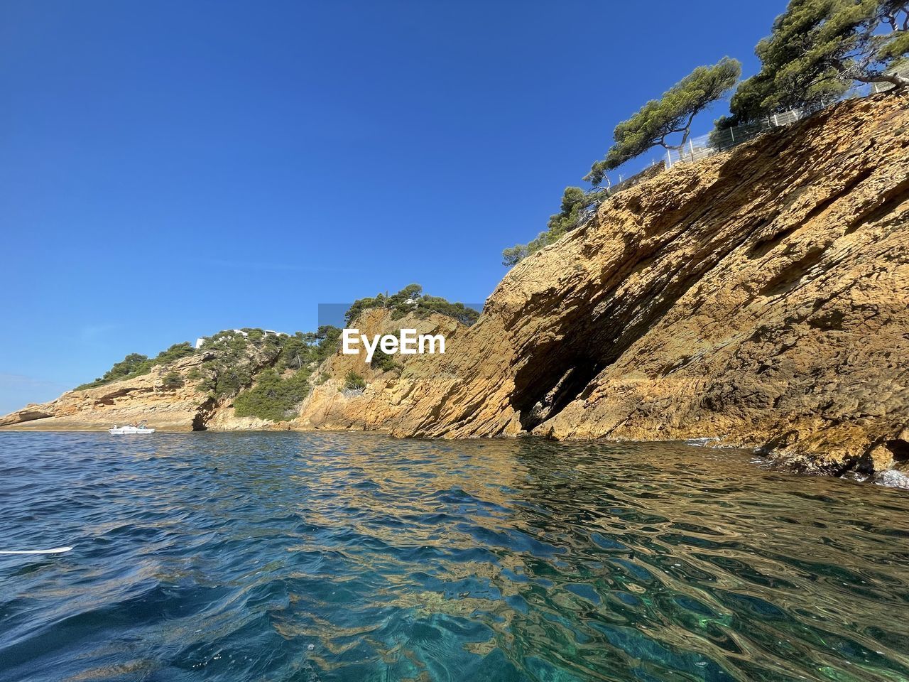 ROCKS ON SEA AGAINST CLEAR BLUE SKY