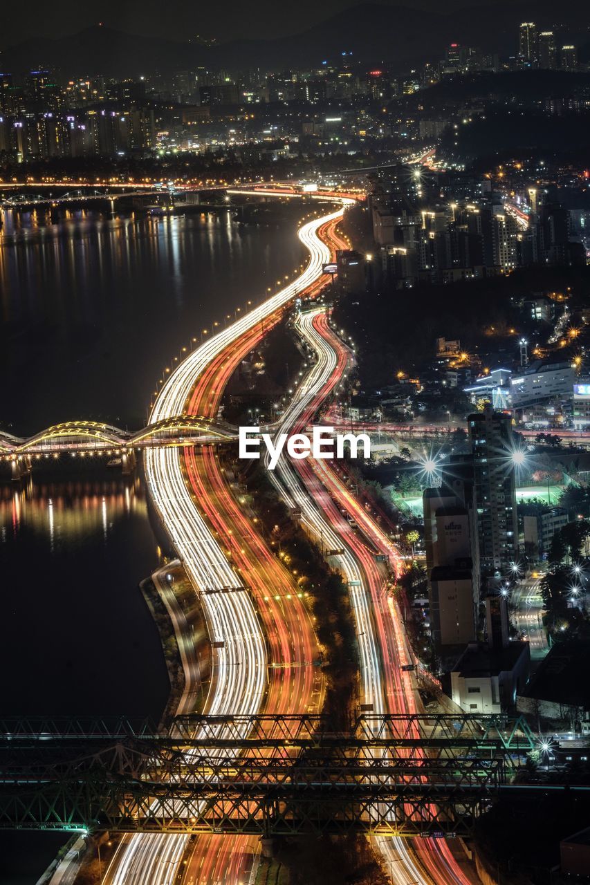 High angle view of illuminated city by buildings at night