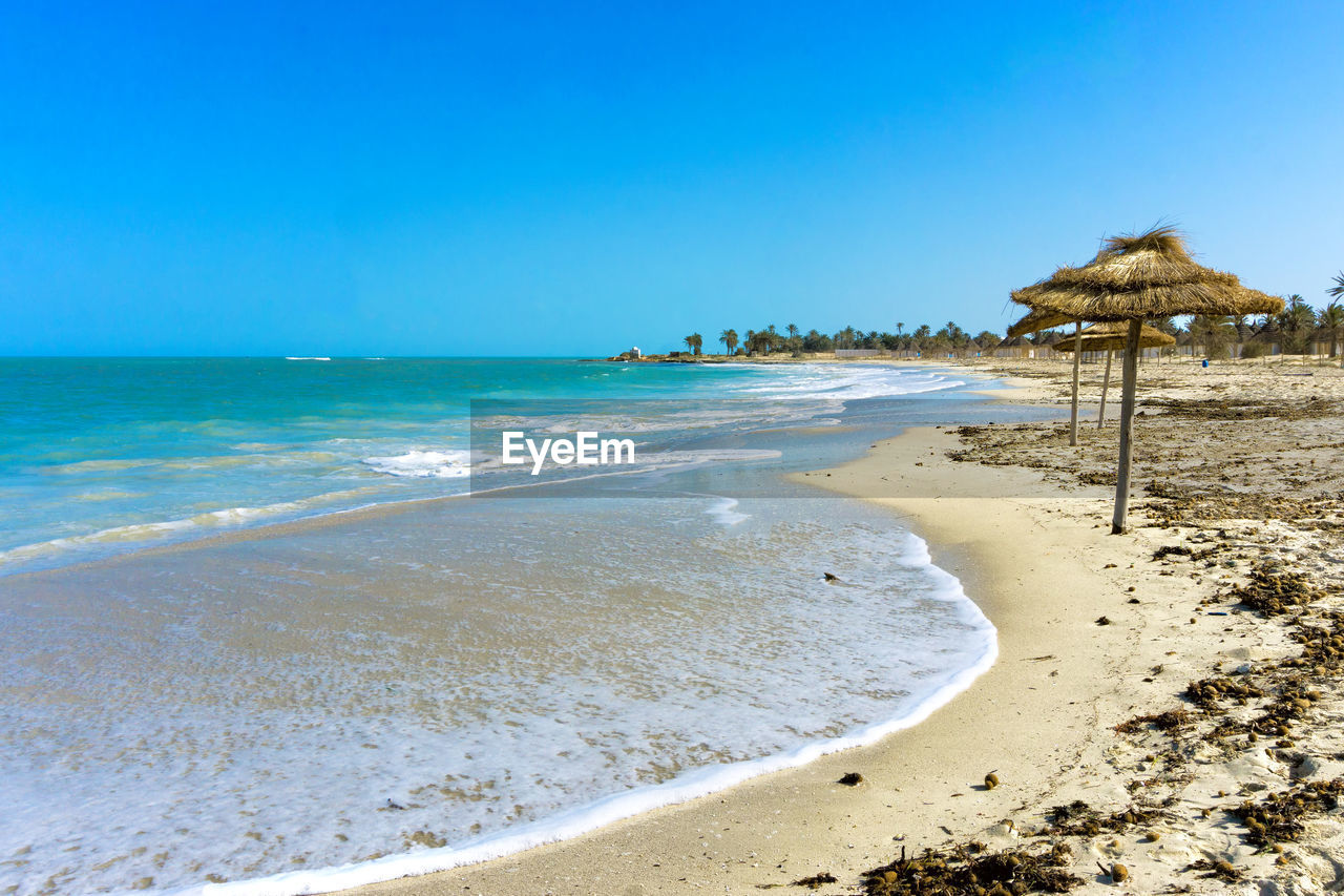 Scenic view of beach against clear blue sky