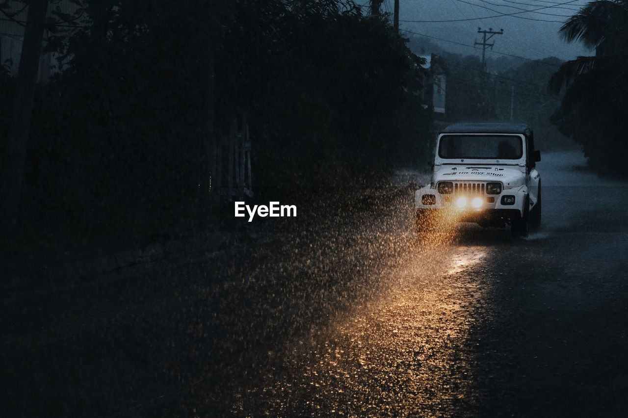 CAR MOVING ON ROAD AT NIGHT DURING RAINY SEASON