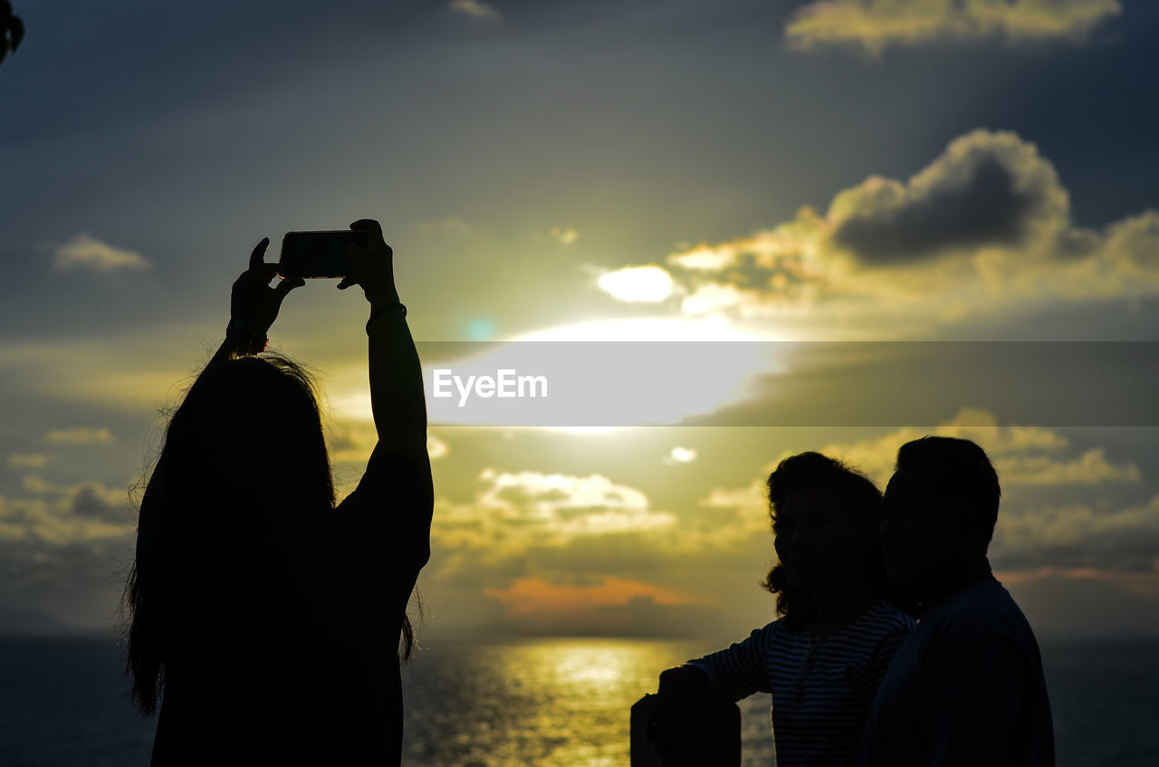 Rear view of silhouette couple against sea during sunset