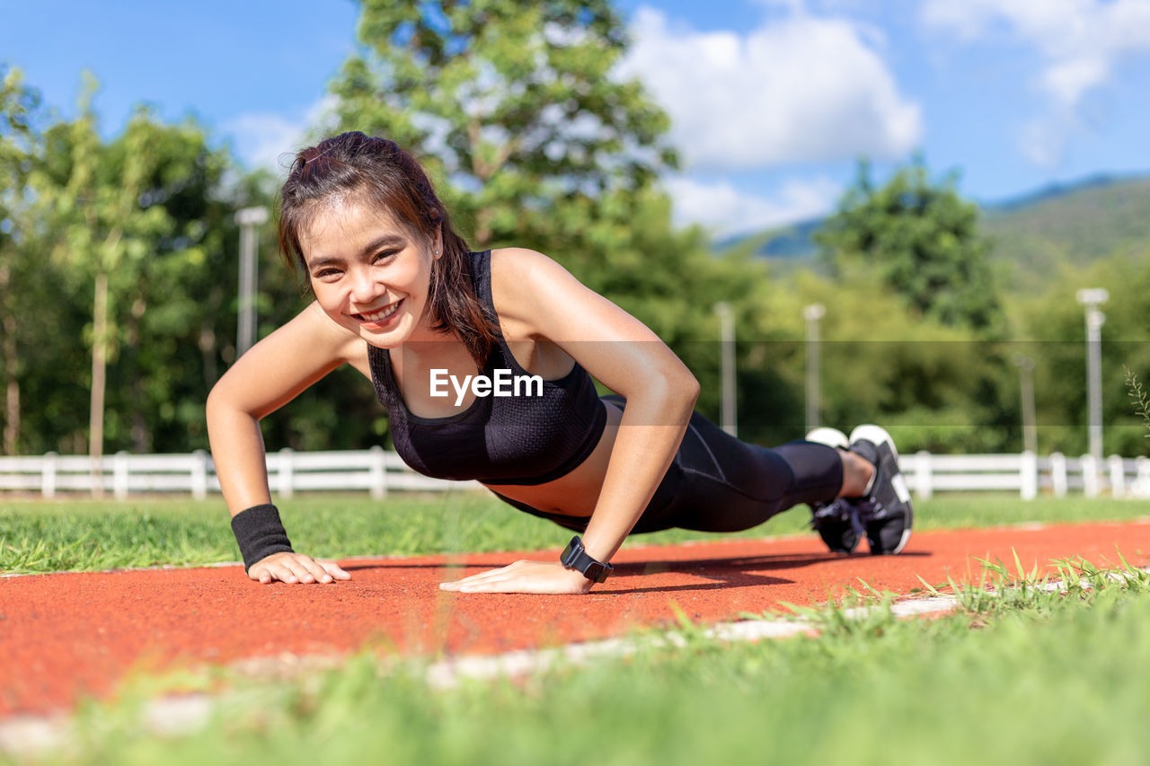 Full length of young woman exercising on sports track