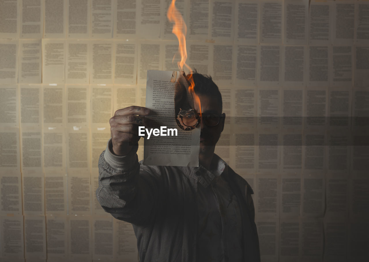 Man holding a burning book sheet and looking through it. conceptual image.