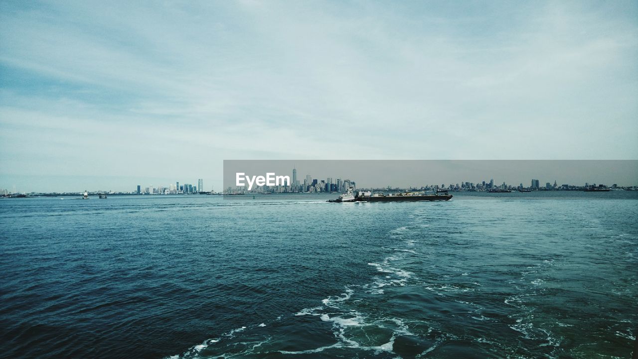 Boats on calm sea against distant new york cityscape