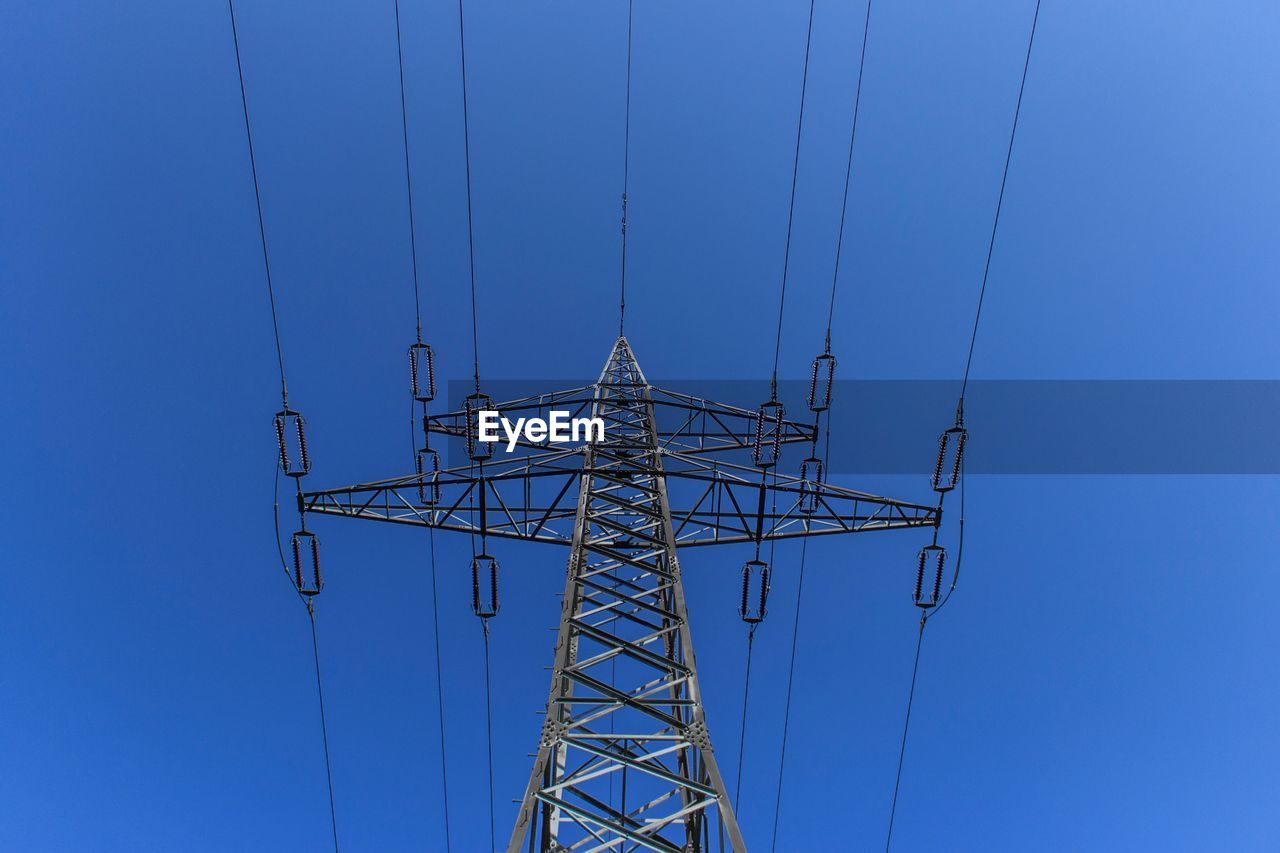 Low angle view of electricity pylon against blue sky