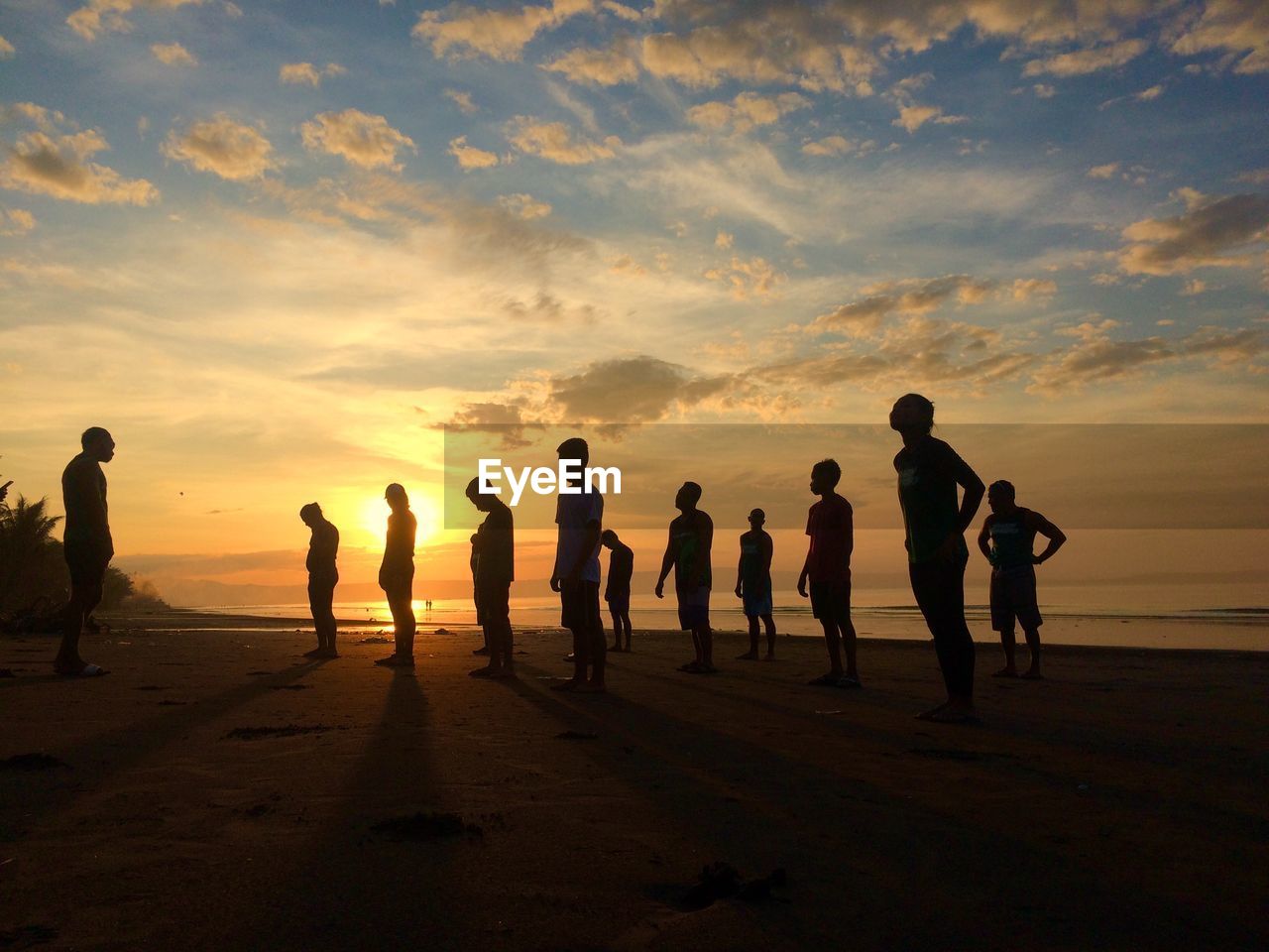 Silhouette people standing at beach against sky during sunset