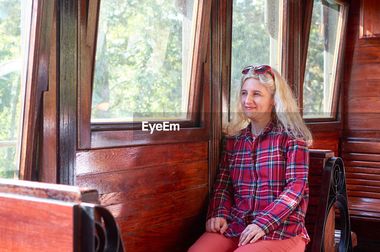 Woman dressed in a royal stewart red tartan shirt sitting in a vintage train - sarganska 8