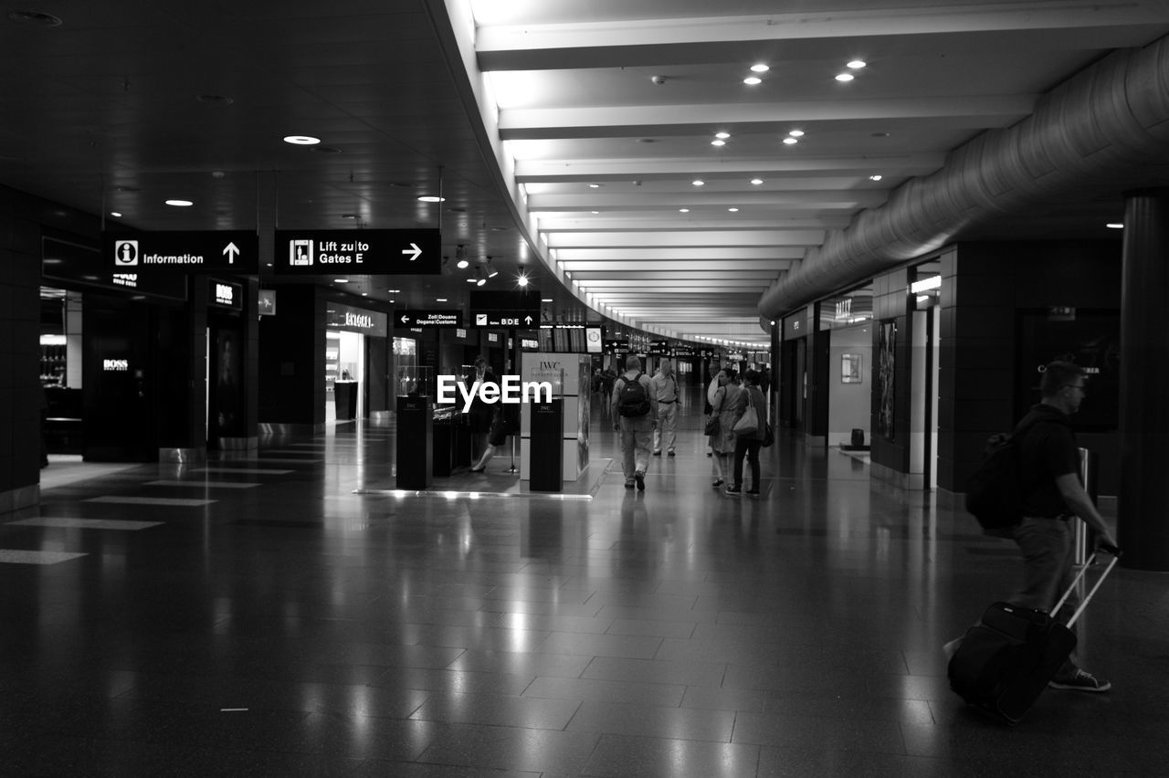 GROUP OF PEOPLE WALKING IN ILLUMINATED UNDERGROUND