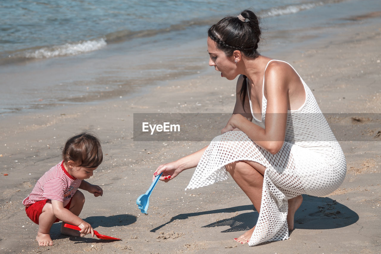 beach, land, sand, childhood, two people, child, water, family, women, adult, female, togetherness, sea, full length, leisure activity, nature, human leg, men, parent, holiday, one parent, person, fun, trip, emotion, lifestyles, vacation, summer, bonding, day, photo shoot, clothing, positive emotion, casual clothing, happiness, love, sports, outdoors, smiling, limb, barefoot, side view