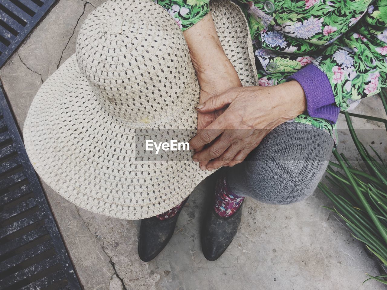 Low section of woman with sun hat sitting outdoors