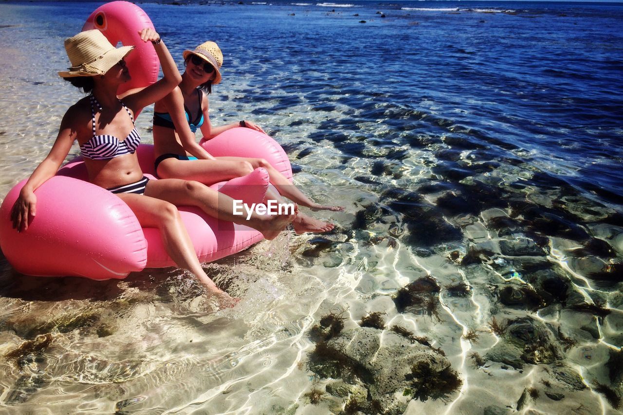 Young women sitting on inflatable raft in sea