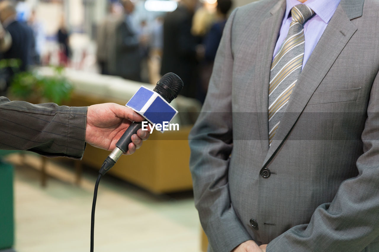 Cropped hand of journalists interviewing man