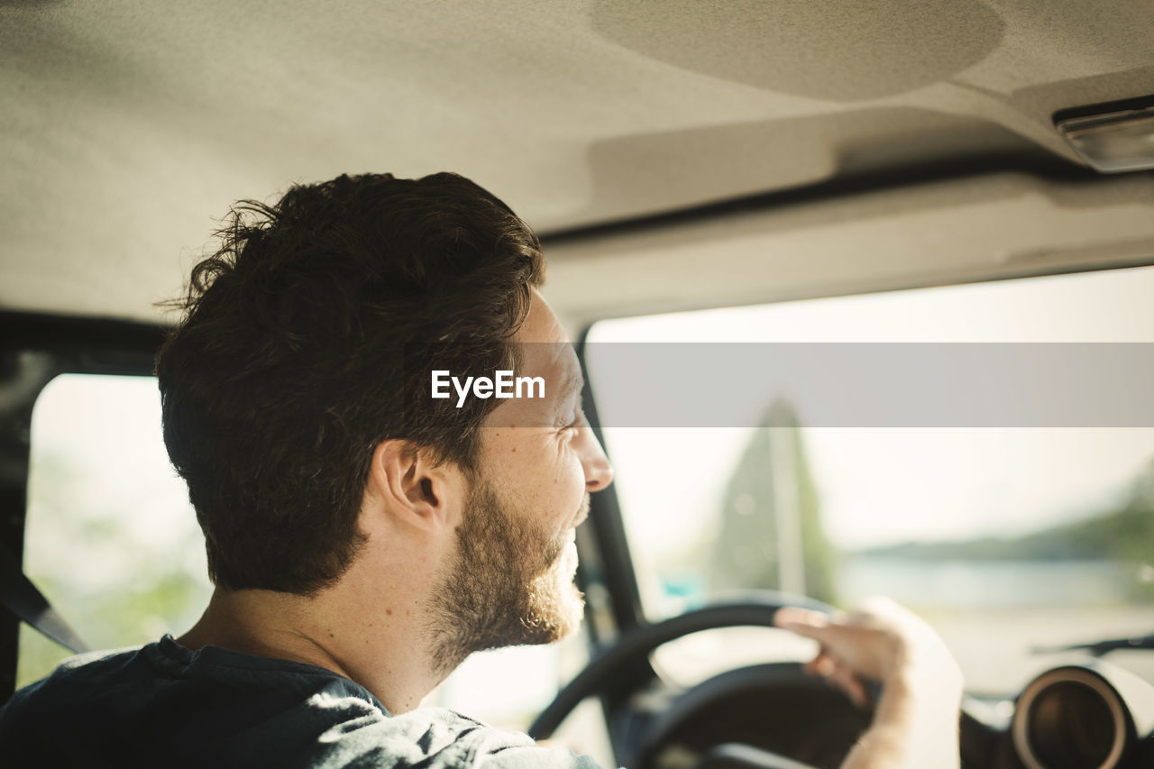 Rear view of happy wonderlust man driving car