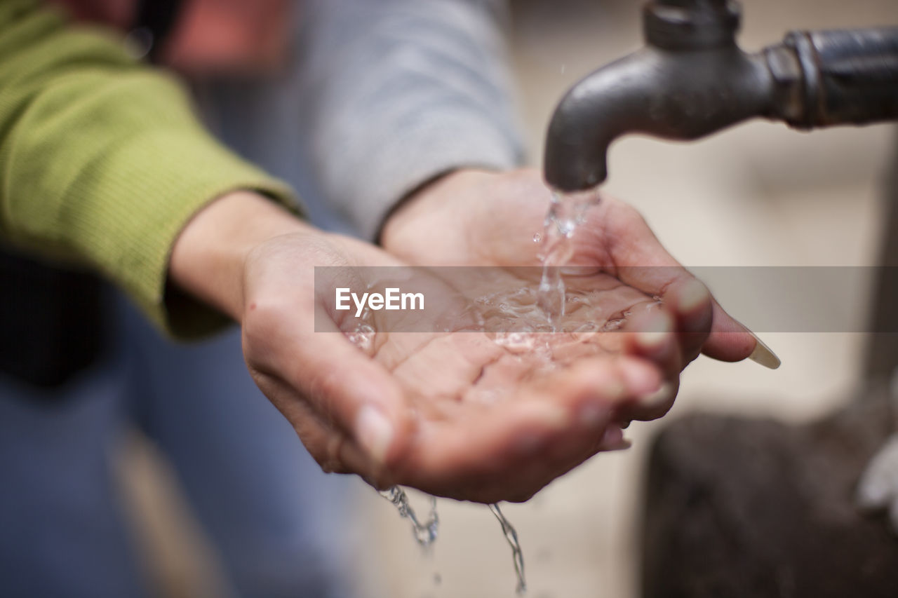 Close-up of woman hand holding water by faucet