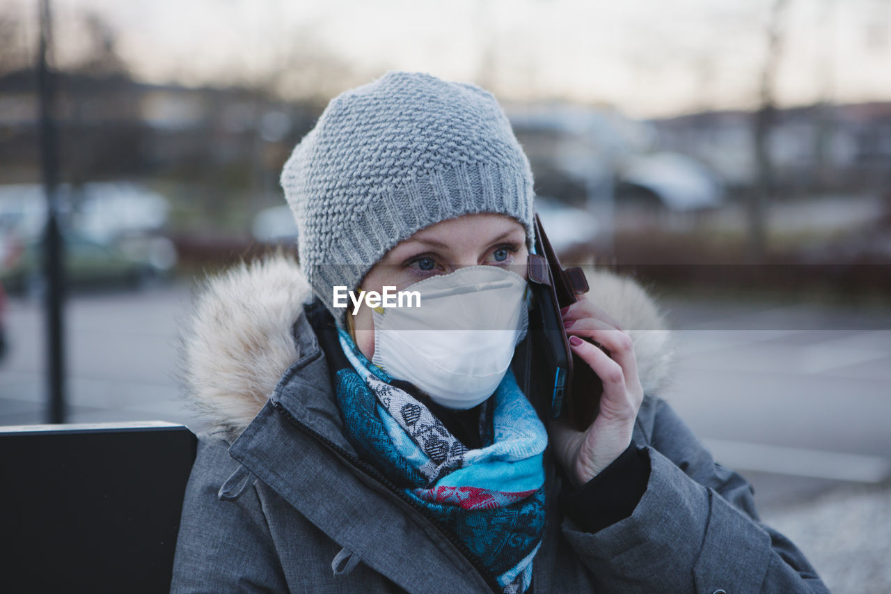 Woman wearing protective mask talking via cell phone