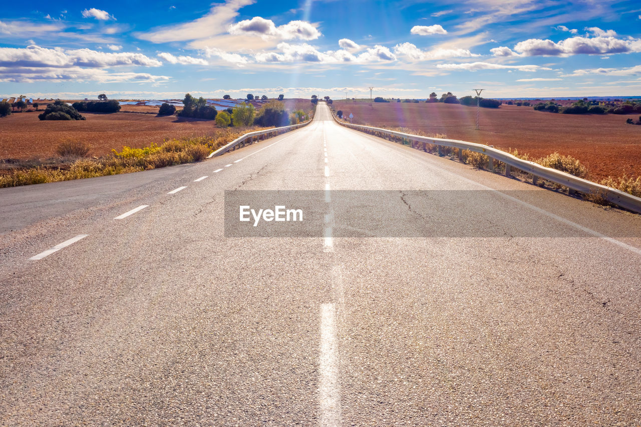 empty road amidst landscape against sky