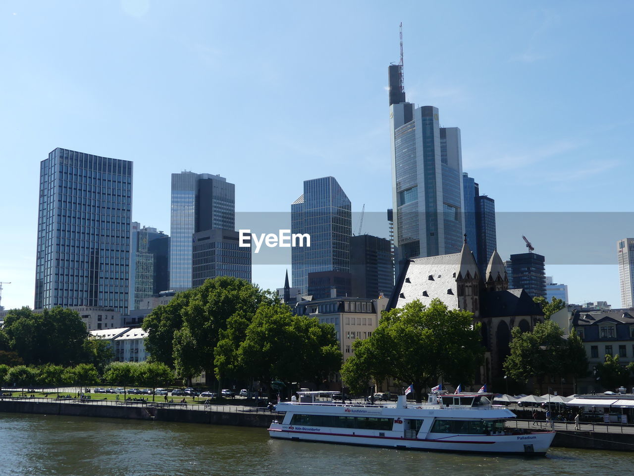 Modern buildings by river against sky in city