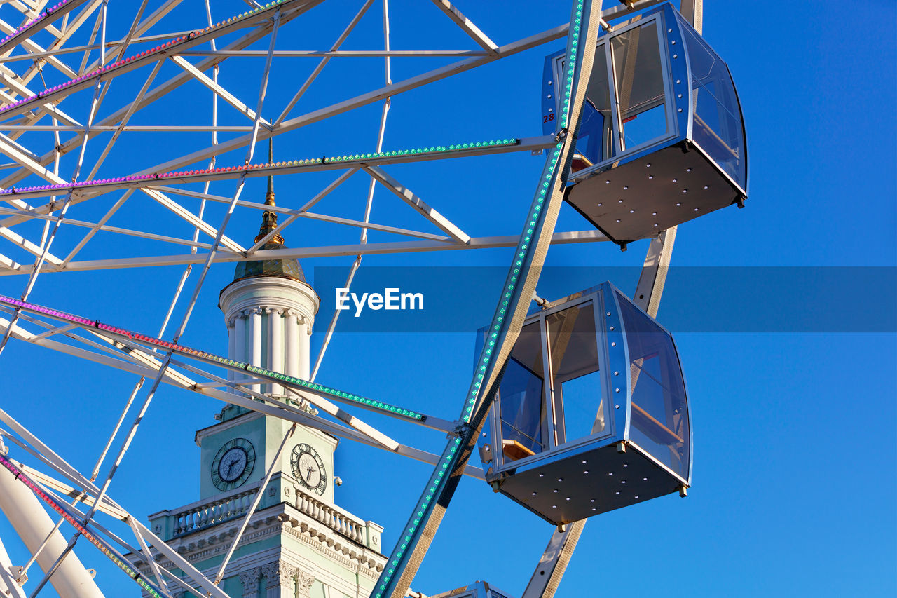 A beautiful and scenic view of the empty cabins of the ferris wheel against the blue sky.