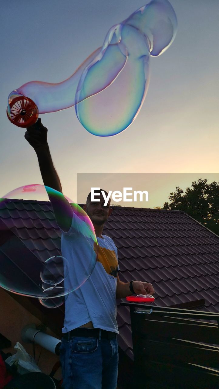 Full length of man with bubbles in background against sky