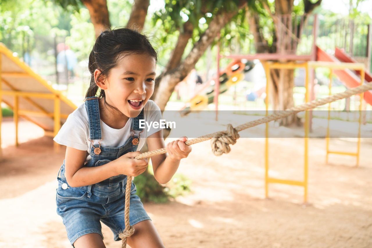 Girl holding rope while playing in playground